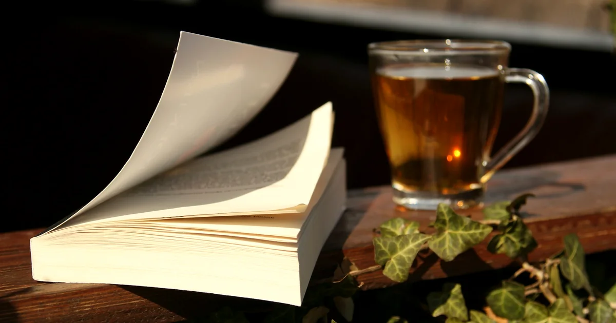 Un livre ouvert et une tasse de thé sur une table en bois